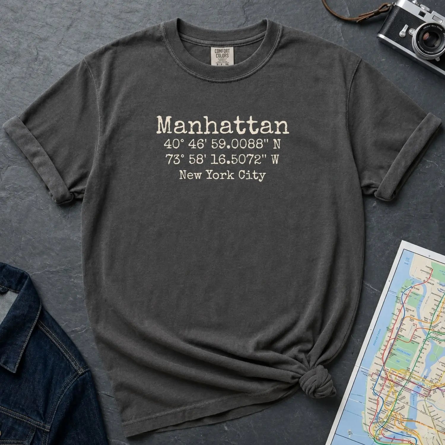 Pepper colored Comfort Colors t-shirt featuring Manhattan, NY coordinates and New York City text in a minimalist typewriter-style design.