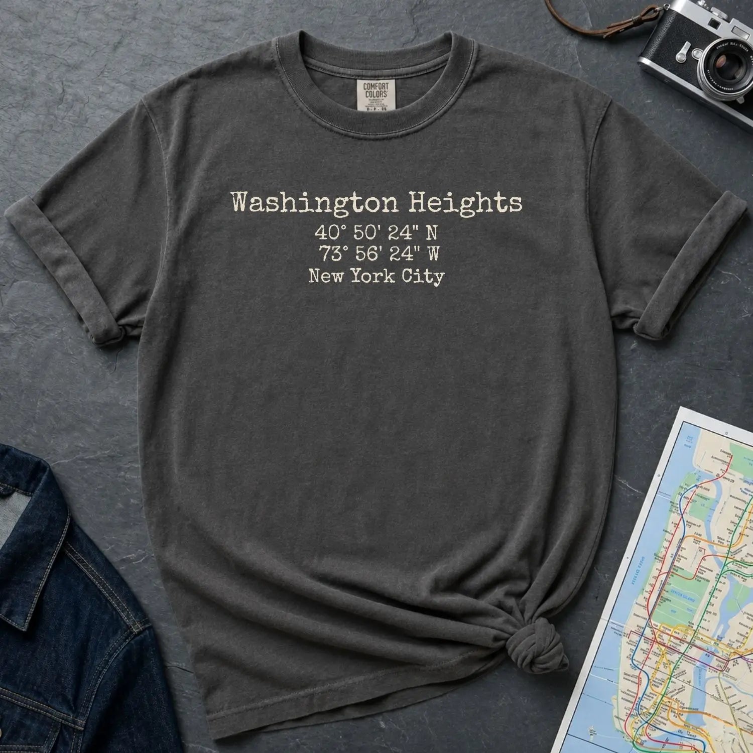 Pepper colored Comfort Colors t-shirt with 'Washington Heights' text with coordinates and 'New York City' on a dark surface with a map and denim jacket.