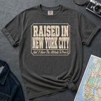 Pepper colored Comfort Colors t-shirt with 'Raised in New York City' text on a dark surface with a map and denim jacket.
