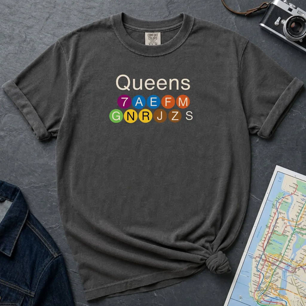 Pepper colored Comfort Colors t-shirt featuring a minimalist Queens subway line graphic with colorful NYC train icons.