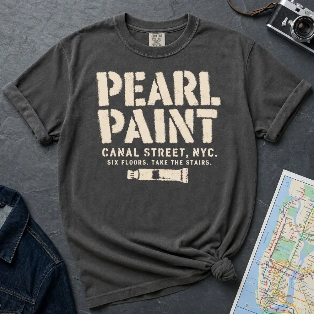 Pepper colored Comfort Colors t-shirt with Pearl Paint in large distressed stencil lettering, Canal Street NYC and Six Floors Take The Stairs below, with a paint tube graphic, displayed on a flat surface with a denim jacket and subway map in the background.