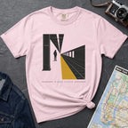 Pink t-shirt with a graphic design of a train station platform, denim jacket, and map on a dark surface
