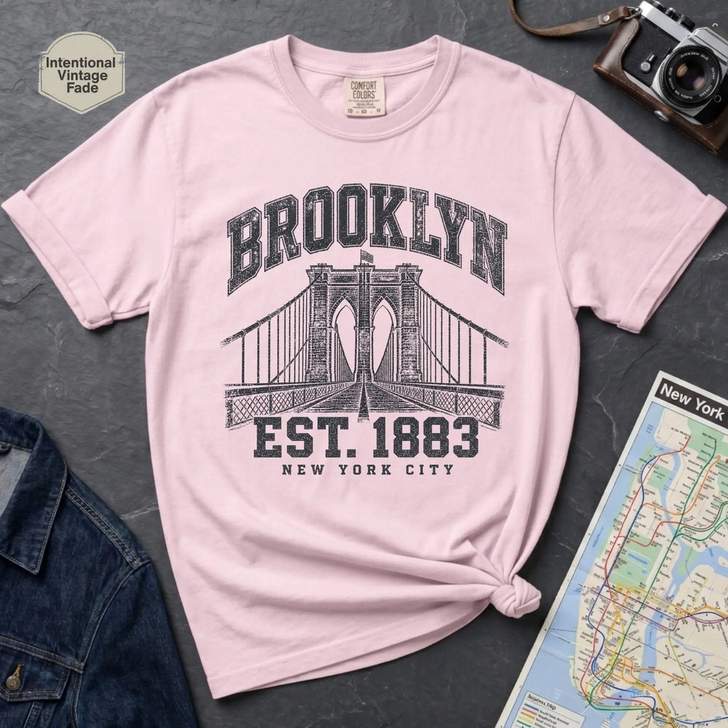 Pink Vintage-style Brooklyn NYC graphic t-shirt on a Bay colored Comfort Colors cotton shirt, featuring the Brooklyn Bridge and “Brooklyn Est. 1883” text.