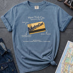 Blue t-shirt with New York City MetroCard graphic on a gray surface with a map and jacket.