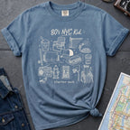 Blue Comfort Colors t-shirt with an 80’s NYC Kid starter pack graphic featuring Italian ice, stickball, a fire hydrant, corner coffee, and stoop illustrations.