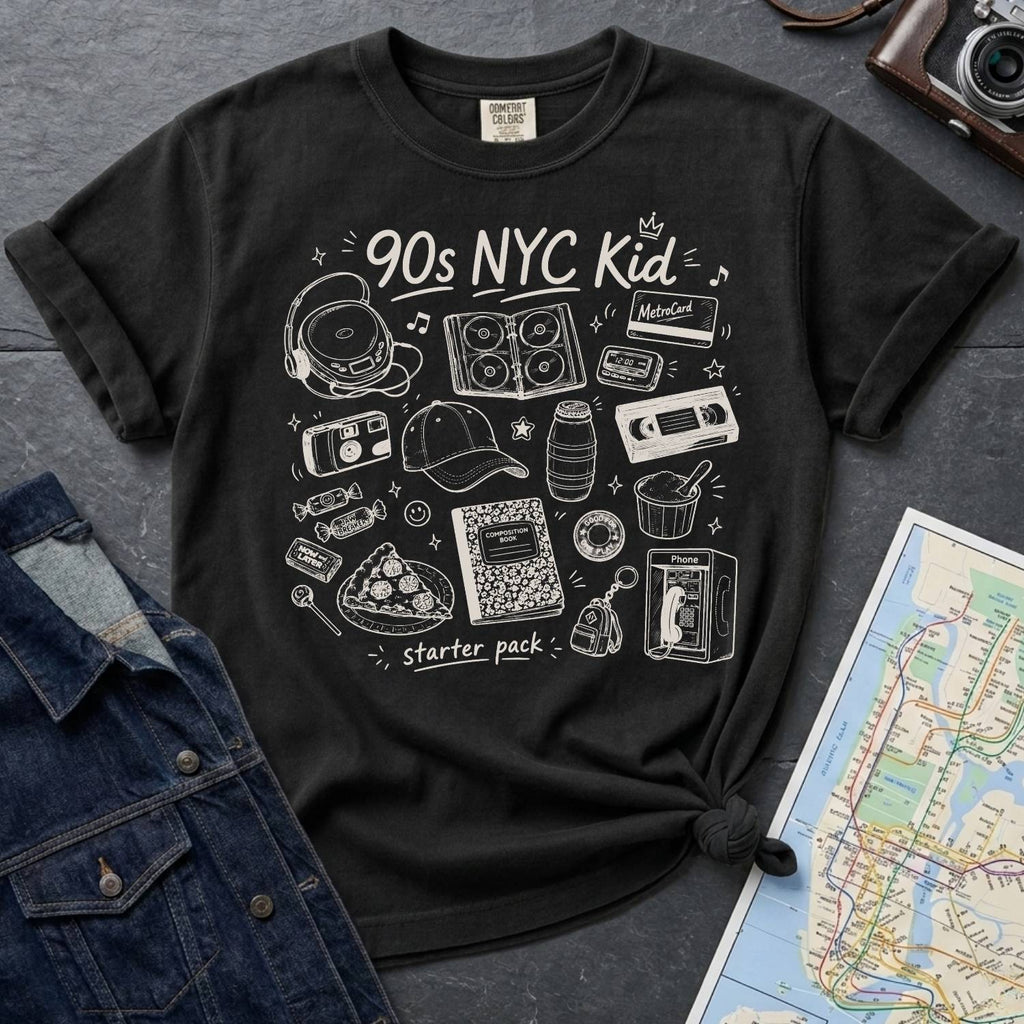 Black Comfort Colors t-shirt with '90s NYC Kid' graphic design on a dark surface with denim jacket and map.