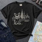 Black t-shirt with a French Bulldog and cityscape design on a gray surface with a denim jacket and a map.