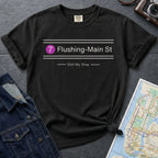 Black t-shirt with 'Flushing-Main St' design on a gray surface with a map and denim jacket.