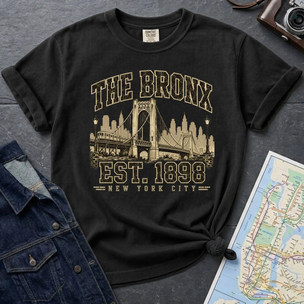 Black t-shirt with 'The Bronx Est. 1898' design on a dark surface with a map and a denim jacket.