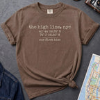 Espresso colored t-shirt with text 'the high line, ny' and coordinates on a dark surface with denim jacket and map.