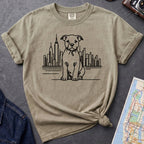 Khaki colored t-shirt with a Pitbull dog and cityscape design on a dark surface with jeans and a map.