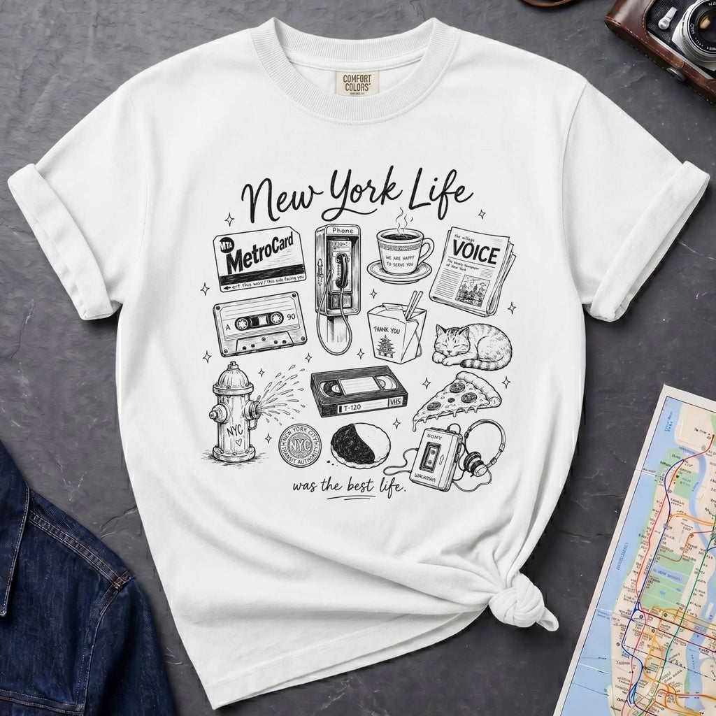 White t-shirt with New York-themed graphics on a gray surface with a map and camera.