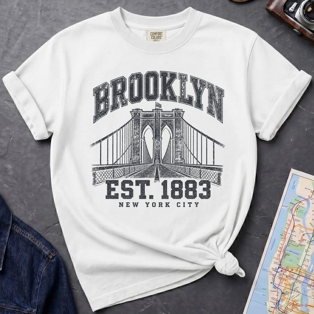 White Vintage-style Brooklyn NYC graphic t-shirt on a Bay colored Comfort Colors cotton shirt, featuring the Brooklyn Bridge and “Brooklyn Est. 1883” text.