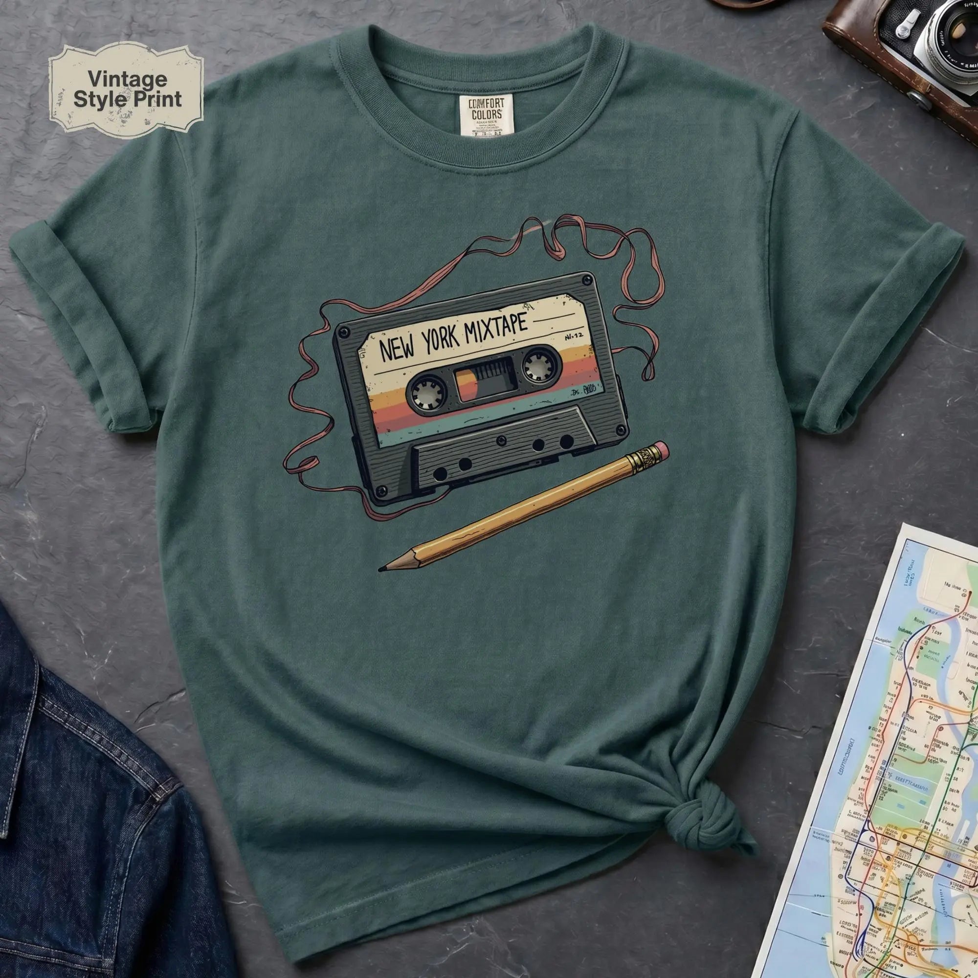 Blue Spruce t-shirt with a cassette tape graphic and pencil on a dark surface