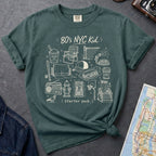 Blue Spruce Comfort Colors t-shirt with an 80’s NYC Kid starter pack graphic featuring Italian ice, stickball, a fire hydrant, corner coffee, and stoop illustrations.