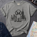 Granite colored t-shirt with a poodle and cityscape design on a dark surface with a map and camera.
