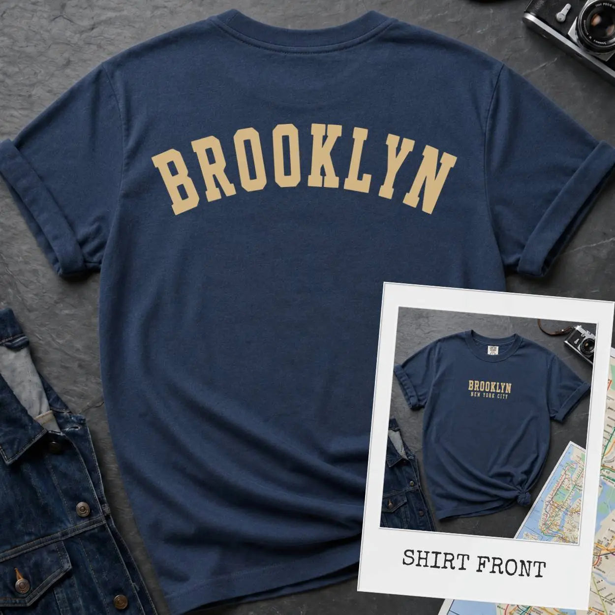 Navy colored Comfort Colors t-shirt with 'Brooklyn' printed on the back and 'Brooklyn, New York City', on a dark surface. 