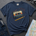 Navy t-shirt with a cassette tape graphic and pencil on a gray surface with denim jacket and map.
