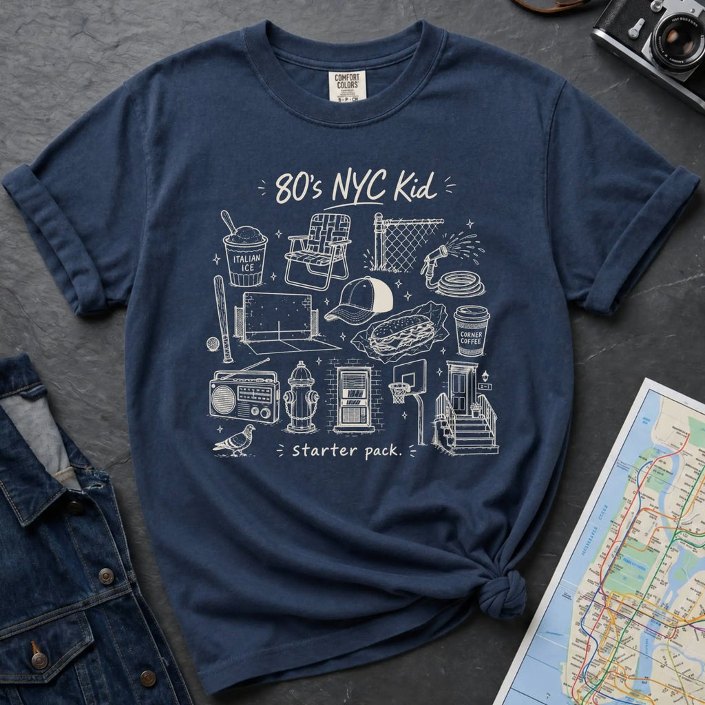 Navy Comfort Colors t-shirt with an 80’s NYC Kid starter pack graphic featuring Italian ice, stickball, a fire hydrant, corner coffee, and stoop illustrations.