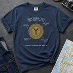 Navy t-shirt with New York City token design on a gray surface with a map and camera.