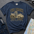 Navy t-shirt with 'The Bronx Est. 1898' design on a dark surface with a map and a denim jacket.