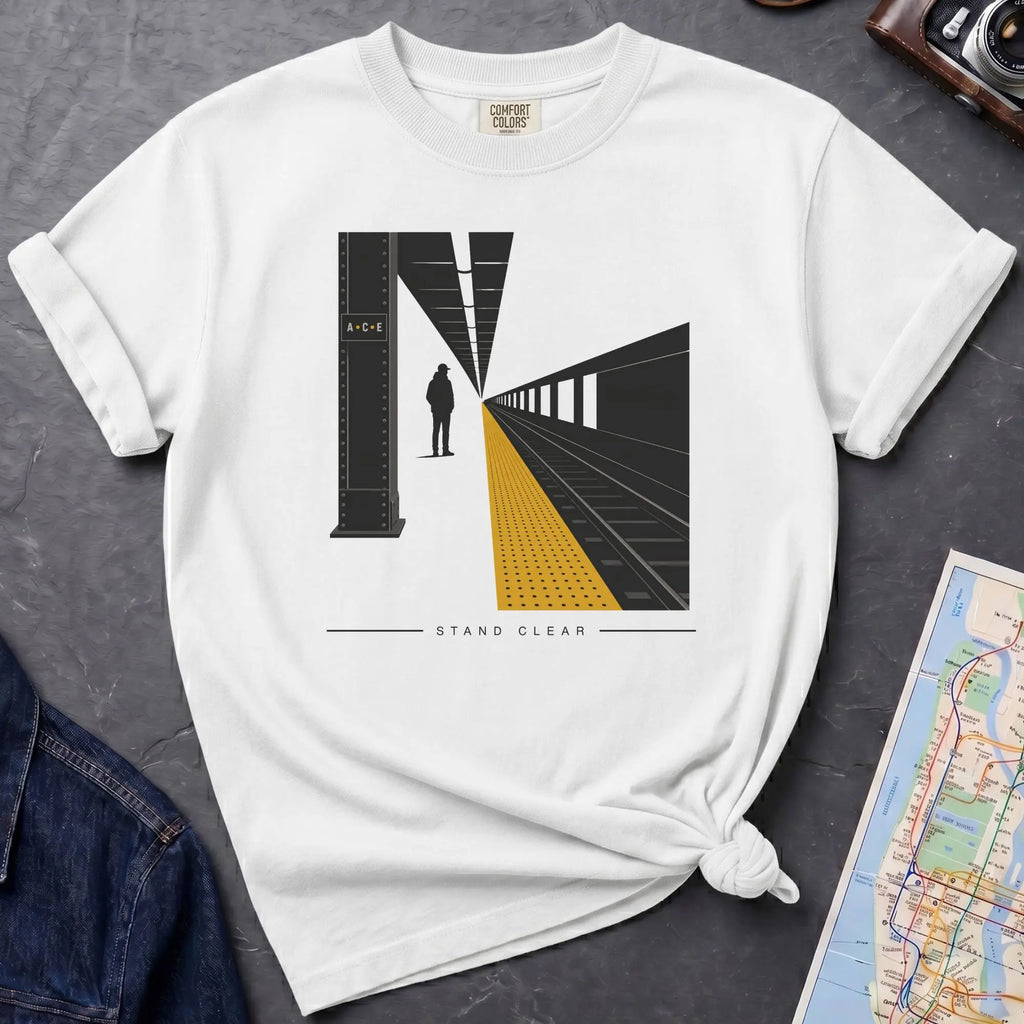 White t-shirt with a graphic design of a train station platform, denim jacket, and map on a dark surface