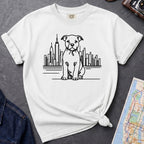 White t-shirt with a Pitbull dog and cityscape design on a dark surface with jeans and a map.