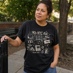 Woman wearing a black Comfort Colors t-shirt with '90s NYC Kid' graphic design while outdoors.