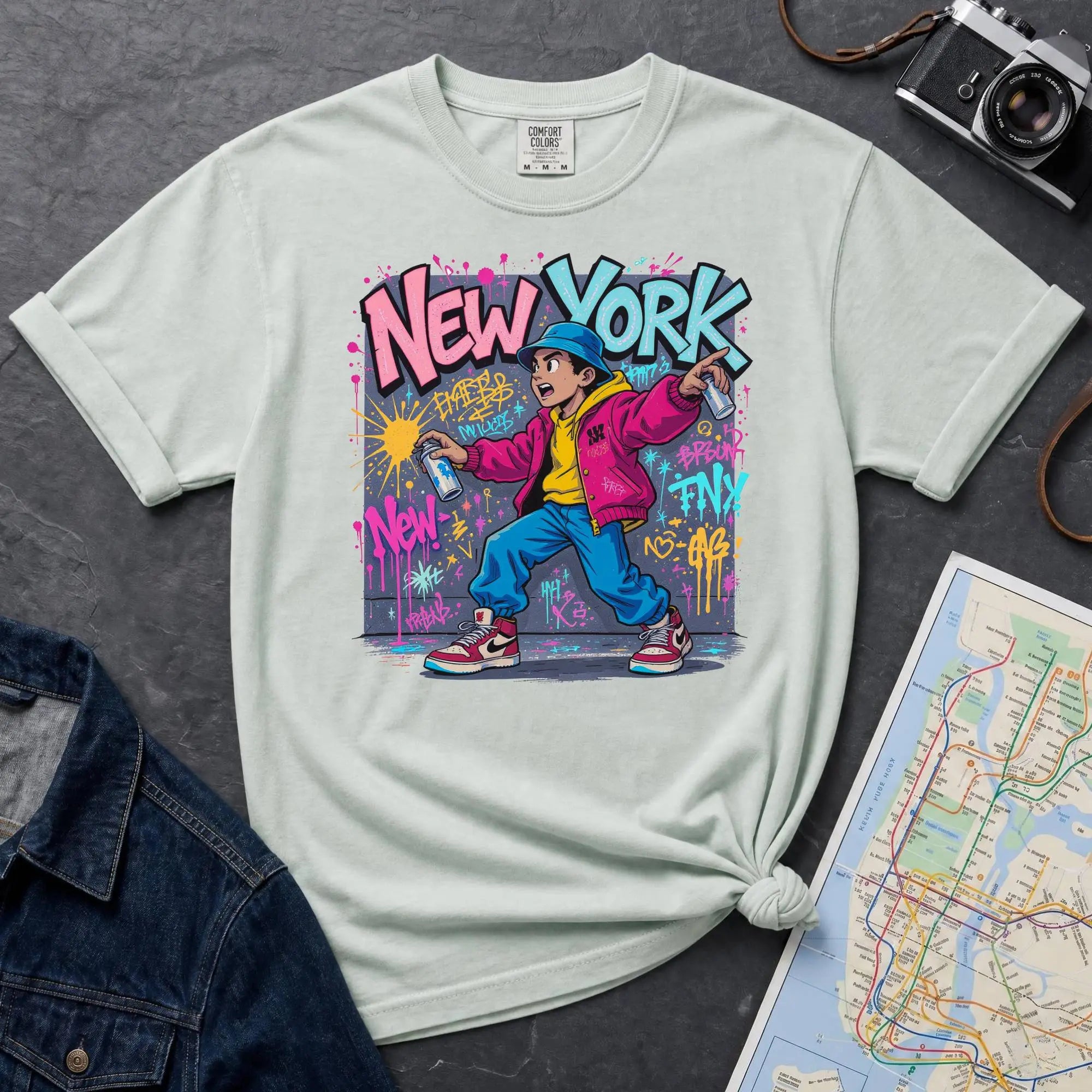 Bay colored Comfort Colors t-shirt featuring a colorful NYC graffiti-style New York graphic with a young street artist holding a spray paint can