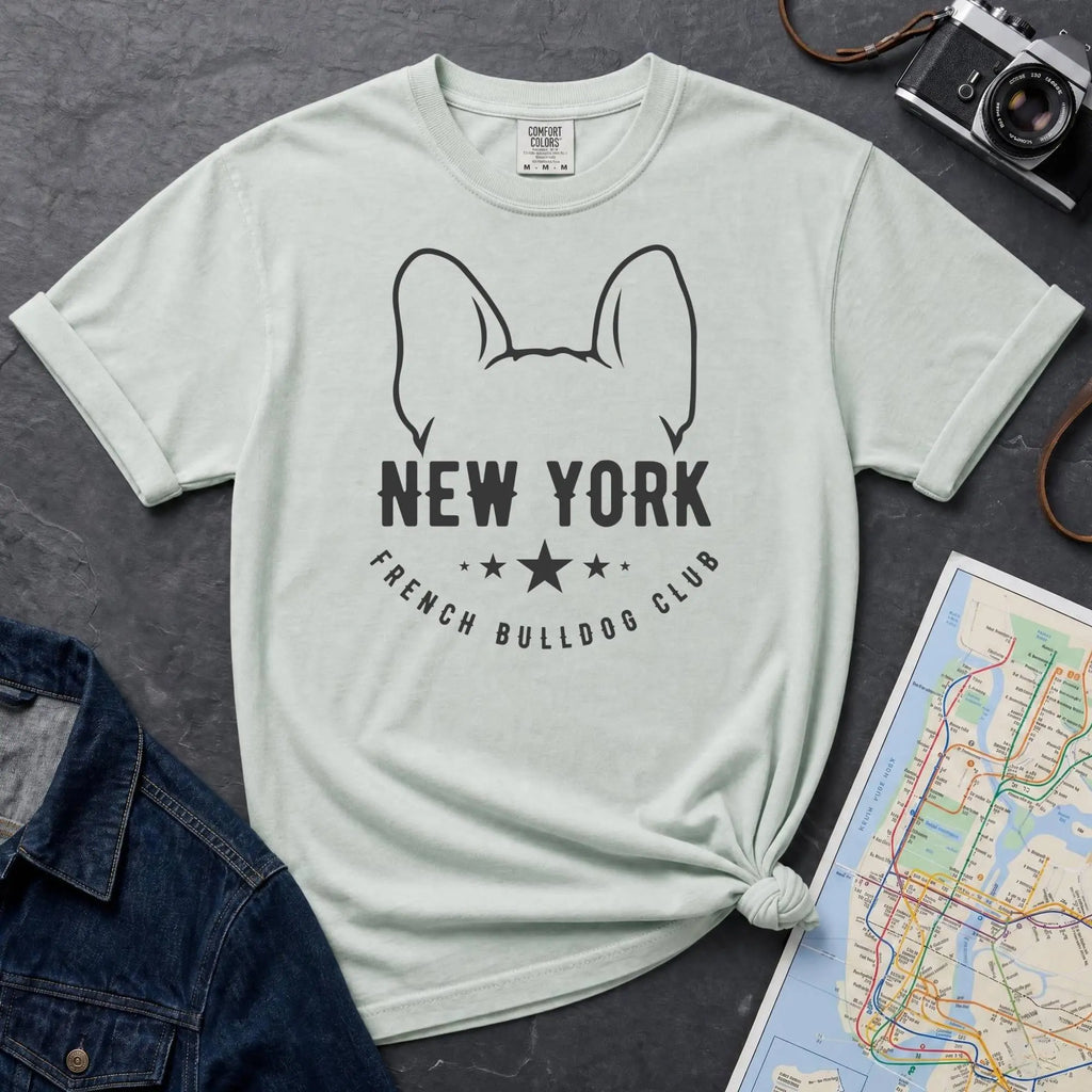Bay colored Comfort Colors t-shirt featuring a New York French Bulldog Club graphic with bold text, outlined French bulldog ears, stars, and a minimalist black design.