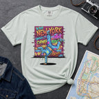 Bay colored t-shirt with a colorful graphic design featuring a breakdancer and text on a dark surface with a denim jacket and a map.