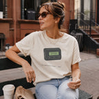 Woman wearing a Ivory Comfort Colors t-shirt featuring a retro pager graphic with “07734” on the screen and “You knew what it said • 1989” text, sitting outdoors.