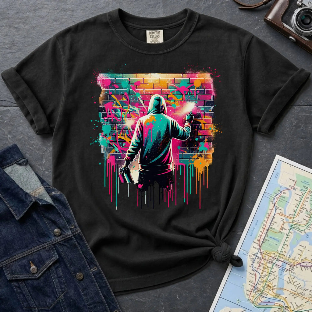 Black t-shirt with a graphic of a person spray painting a colorful mural on a brick wall.