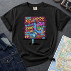 Black Comfort Colors t-shirt featuring a colorful B-Boy New York graphic with a breakdancer in front of a graffiti brick wall.