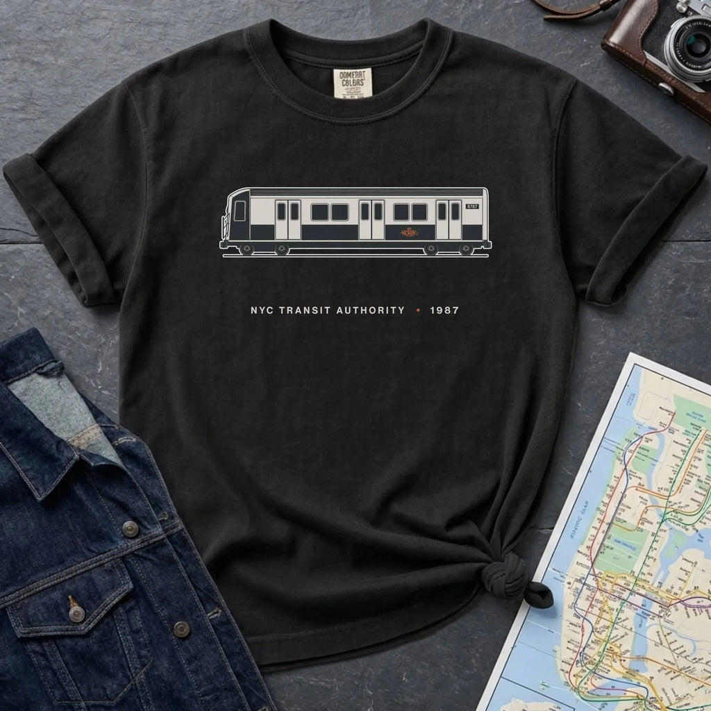Black Comfort Colors t-shirt featuring a minimalist New York City subway car graphic with “NYC Transit Authority • 1987” text.