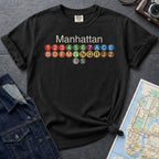 Black Comfort Colors t-shirt featuring a minimalist Manhattan subway line graphic with colorful NYC train icons.