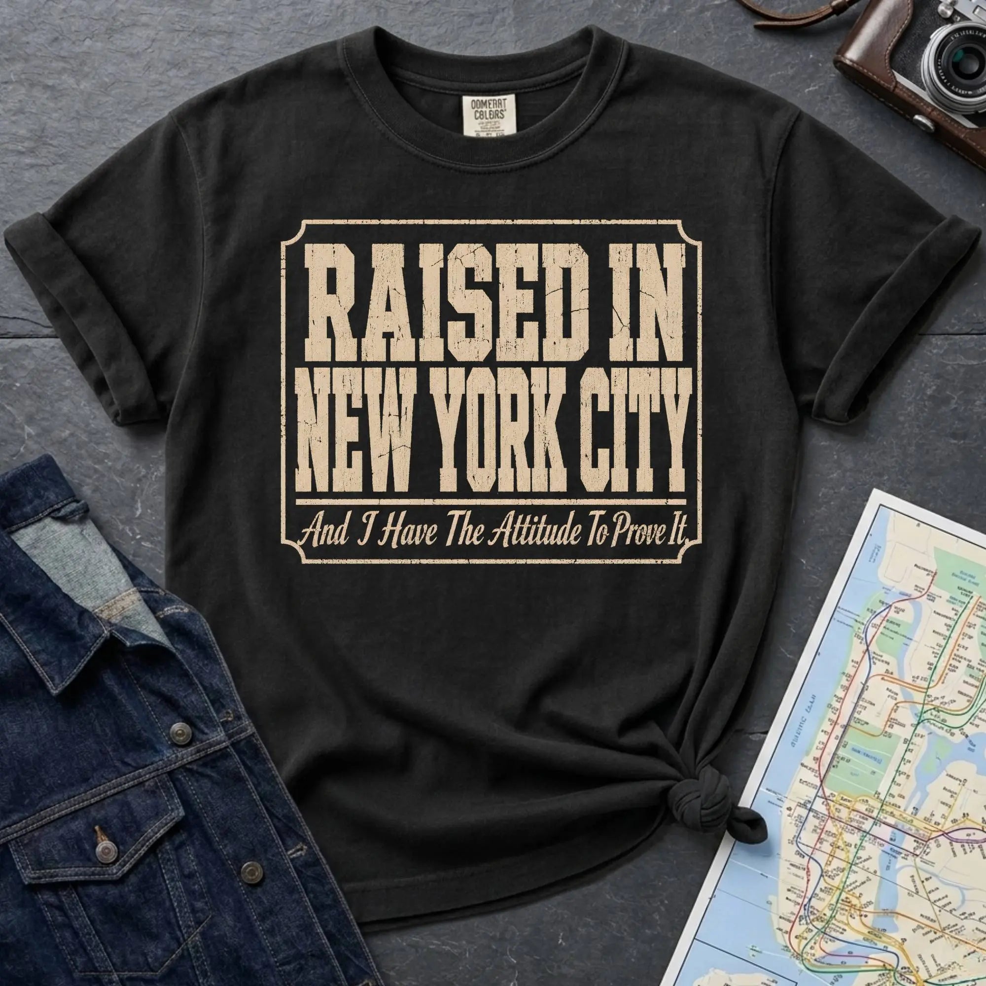 Black Comfort Colors t-shirt featuring distressed vintage text that reads “Raised in New York City, And I Have the Attitude to Prove It.