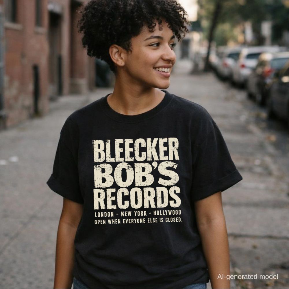 Woman wearing a black Comfort Colors t-shirt with Bleecker Bob's Records in large distressed block lettering, London, New York, Hollywood and Open When Everyone Else Is Closed below, while walking down a NYC street.