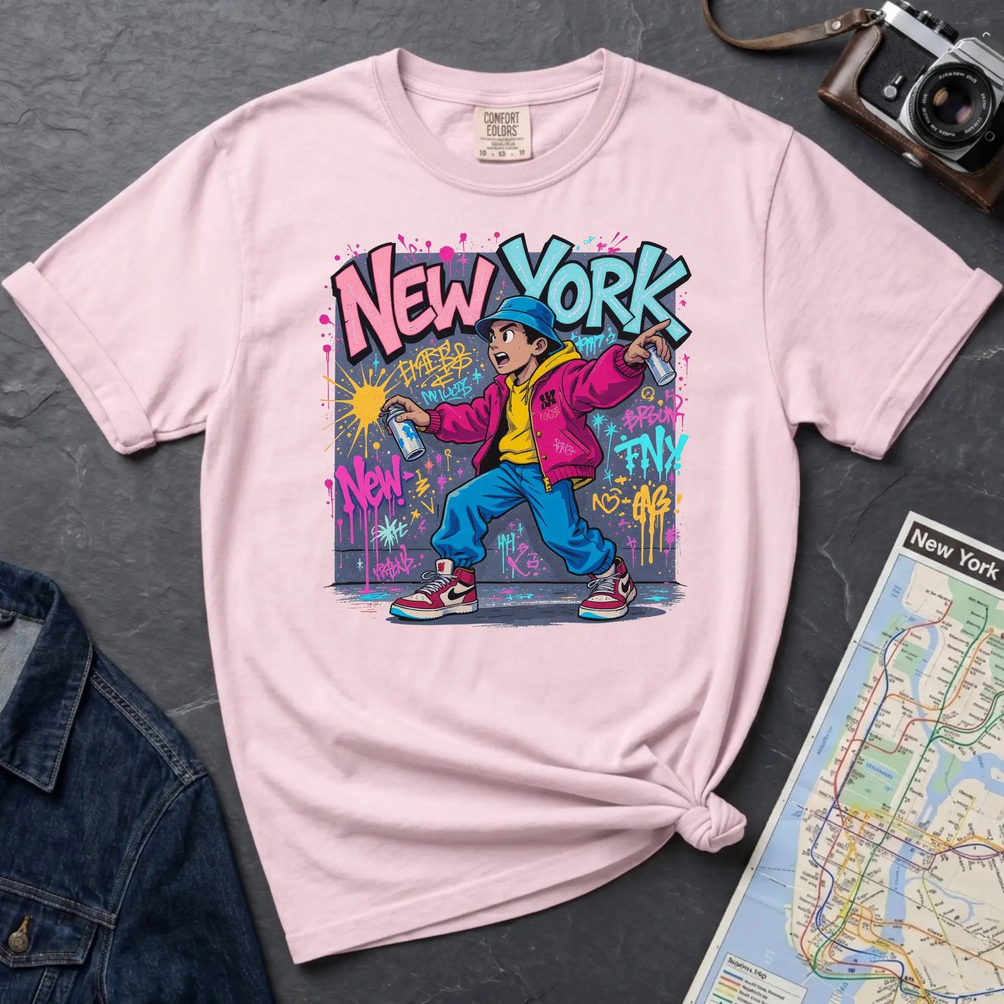 Pink Comfort Colors t-shirt featuring a colorful NYC graffiti-style New York graphic with a young street artist holding a spray paint can