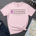 Pink t-shirt with 'Jay St-MetroTech' text on a dark surface with a map and camera.