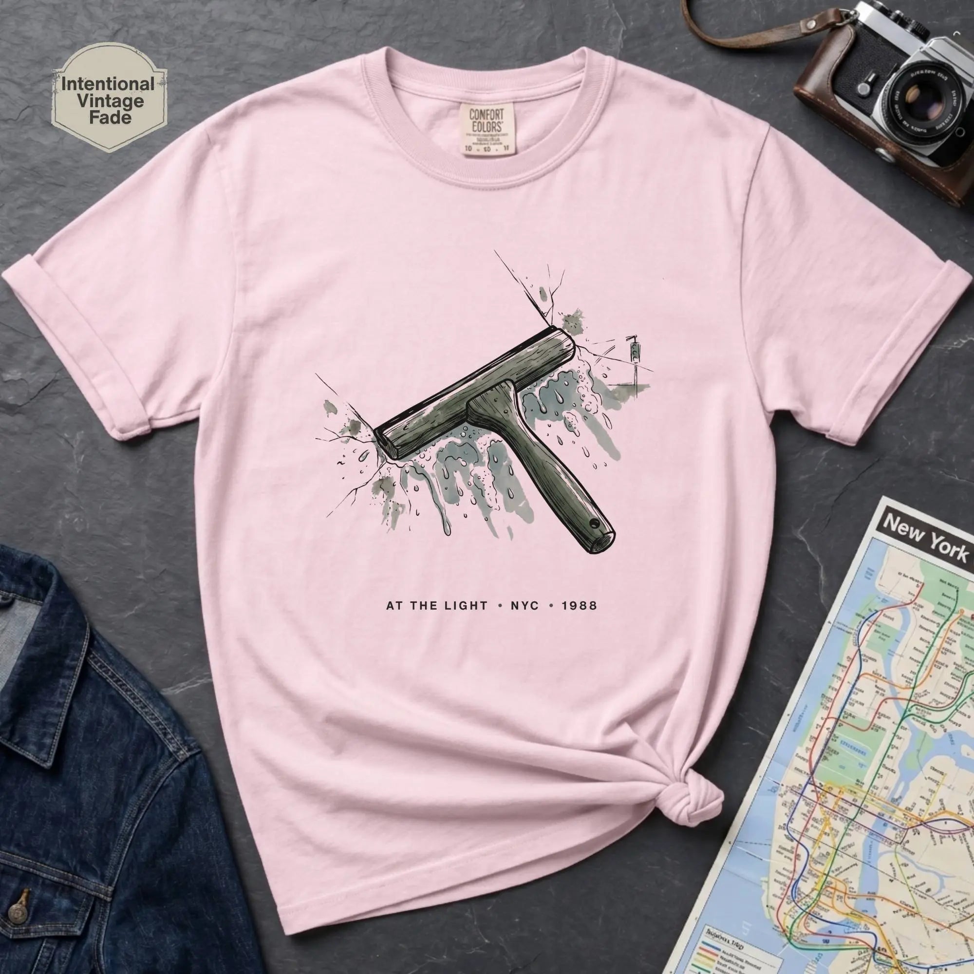 Pink Comfort Colors t-shirt featuring a vintage windshield squeegee graphic with “At the Light • NYC • 1988” text.