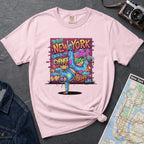 Pink t-shirt with a colorful graphic design featuring a breakdancer and text on a dark surface with a denim jacket and a map.