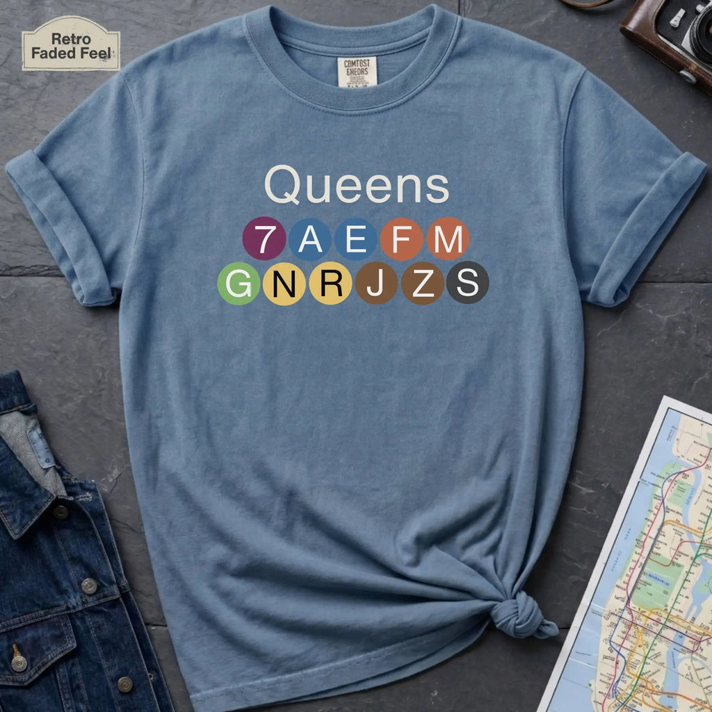 Blue Black Comfort Colors t-shirt featuring a minimalist Queens subway line graphic with colorful NYC train icons.