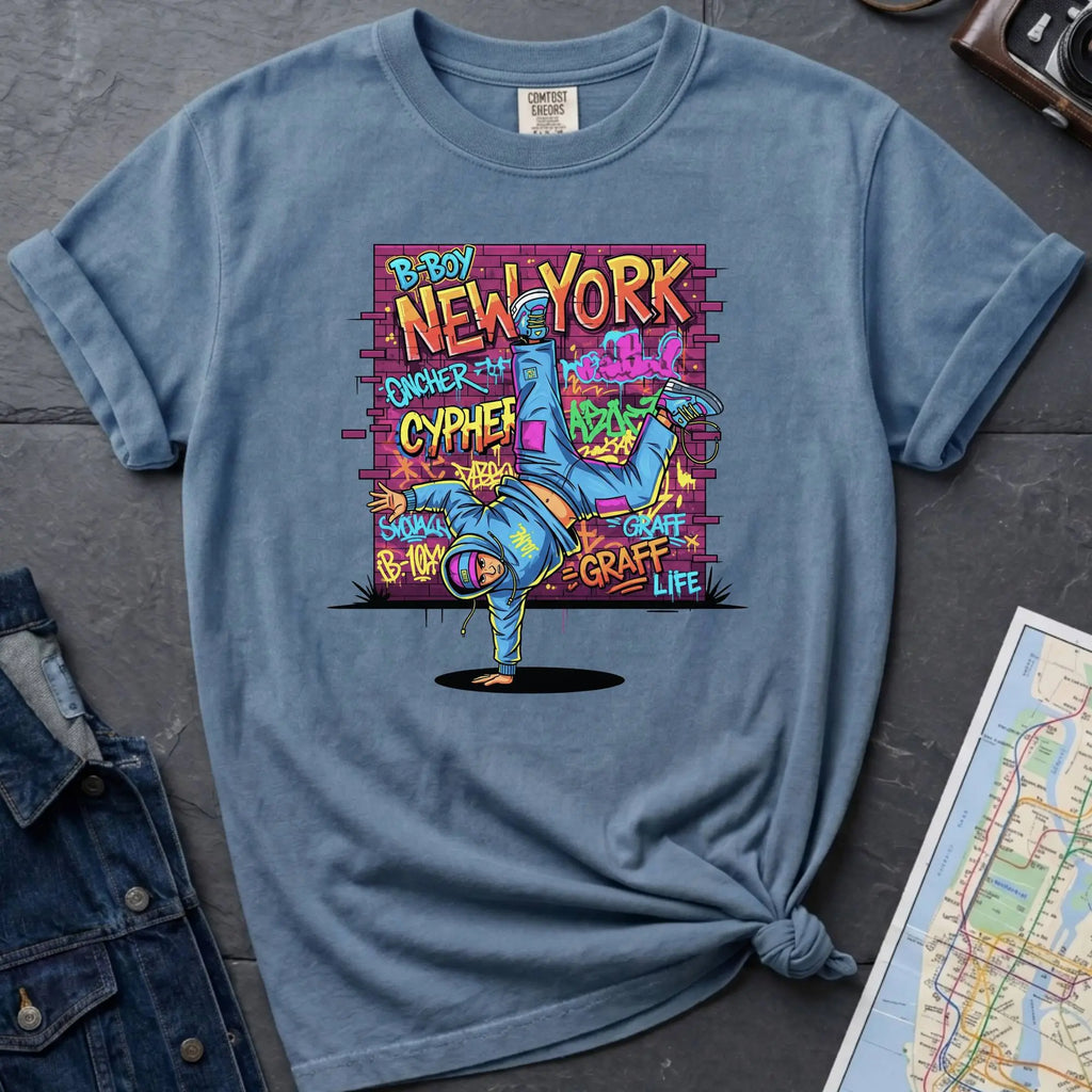 Blue Comfort Colors t-shirt featuring a colorful B-Boy New York graphic with a breakdancer in front of a graffiti brick wall.