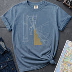 Blue Comfort Colors t-shirt featuring a minimalist NYC subway platform graphic with a lone figure, train tracks, and “Stand Clear” text.