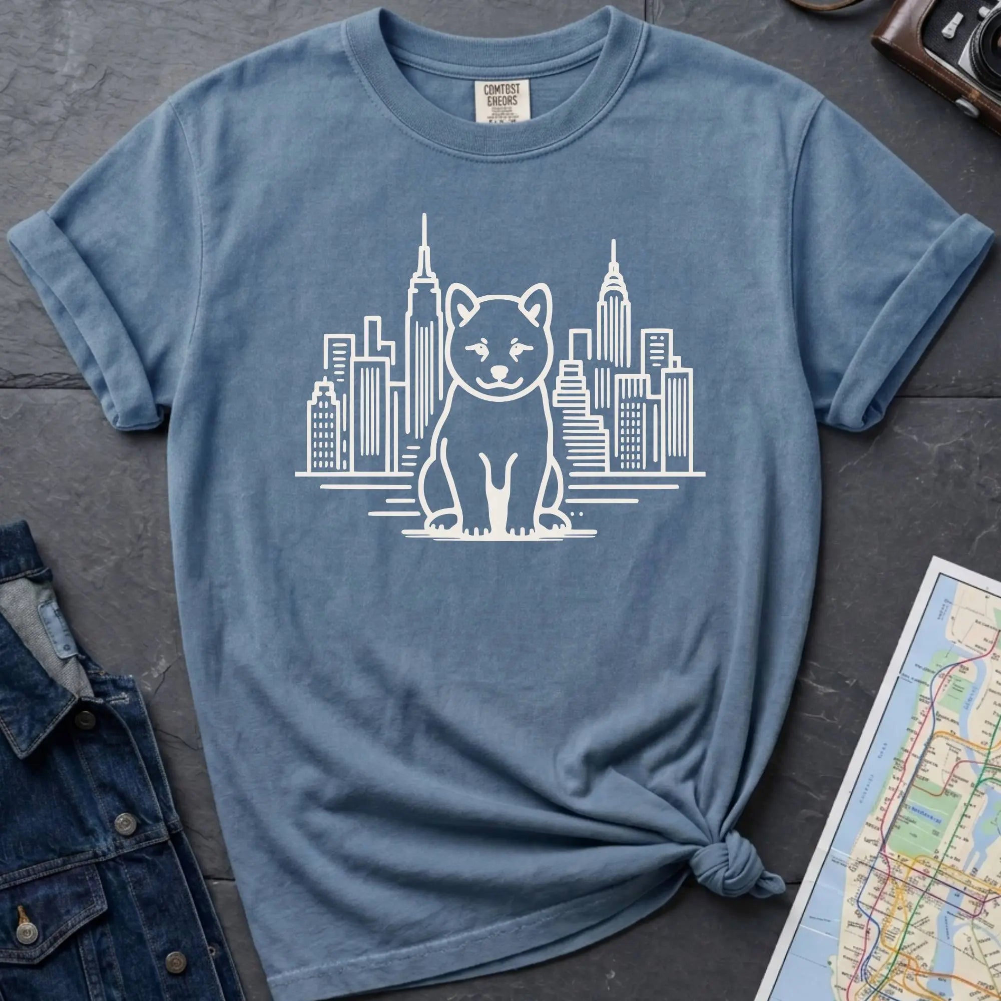 Blue Comfort Colors t-shirt featuring a minimalist Shiba Inu graphic in front of the New York City skyline.