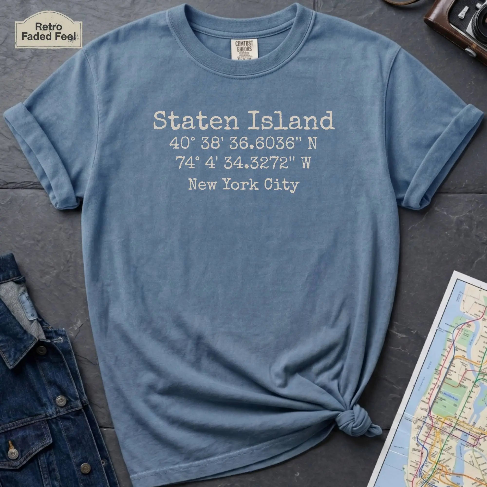 Blue Comfort Colors t-shirt featuring a minimalist Staten Island coordinates design with “Staten Island,” latitude and longitude, and “New York City” printed in a vintage-style font.