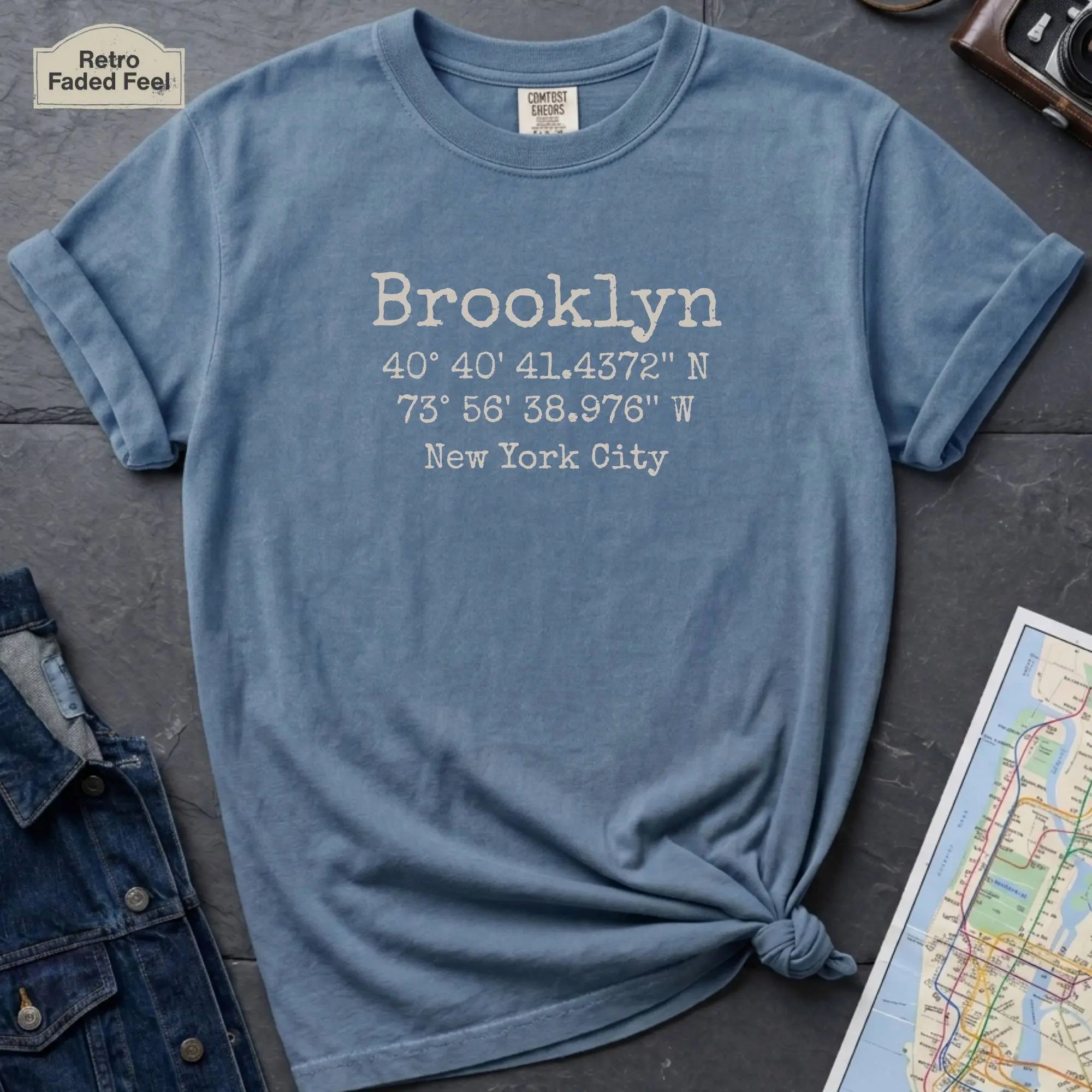 Blue Comfort Colors t-shirt featuring Brooklyn, NY coordinates and New York City text in a minimalist typewriter-style design.