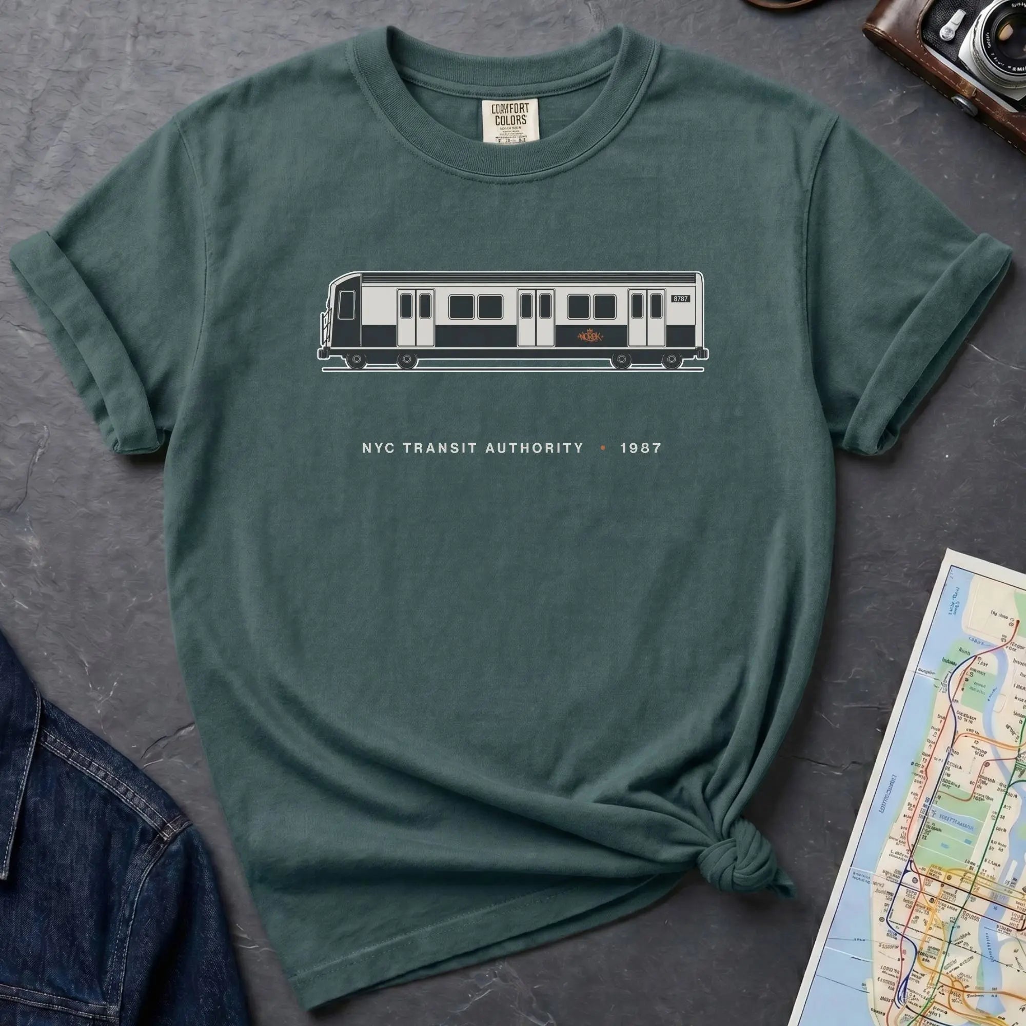 Blue Spruce Comfort Colors t-shirt featuring a minimalist New York City subway car graphic with “NYC Transit Authority • 1987” text.