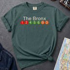 Blue Spruce Comfort Colors t-shirt featuring a minimalist Bronx subway line graphic with The Bronx text and colorful NYC train icons.